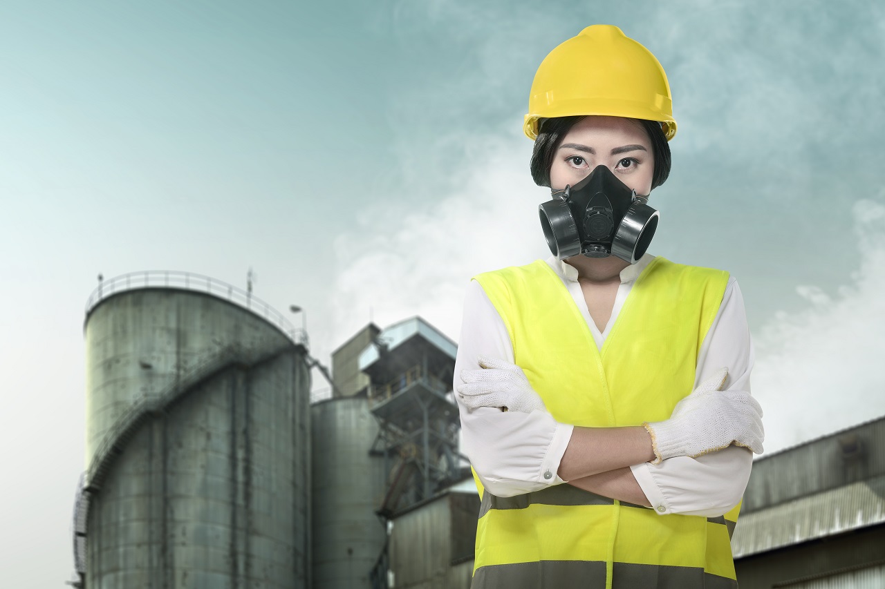 A female factory employee wearing a gas mask to combat air pollution