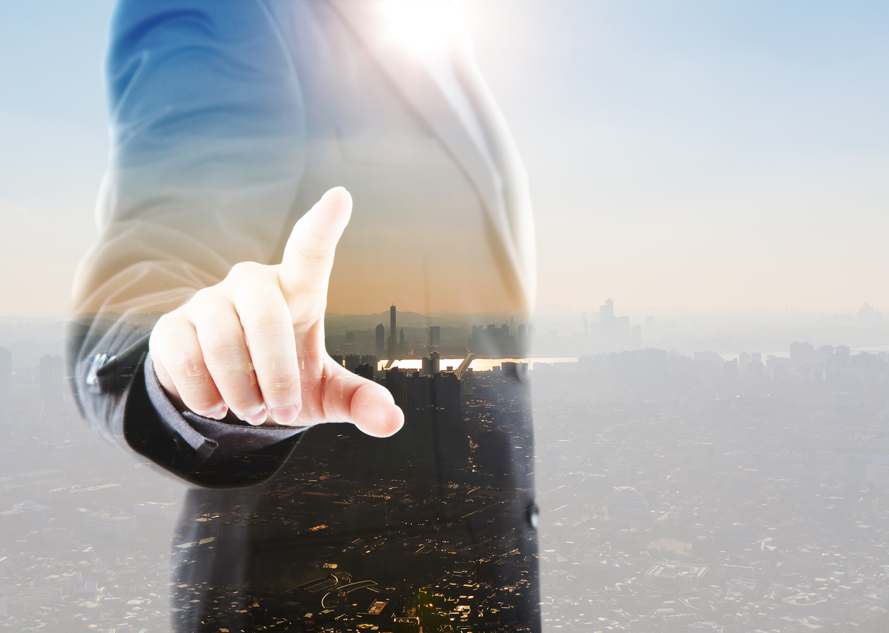 A business man pointing to a city from industrial park